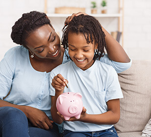 mother and son putting money in a piggy bank